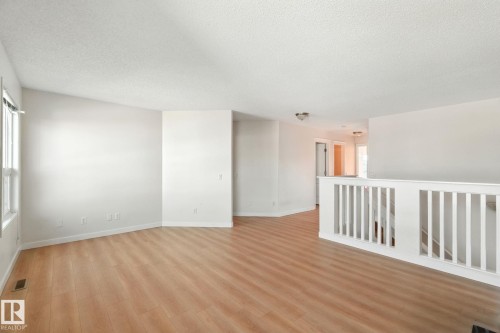 Unfurnished room featuring a textured ceiling and light wood-style floors - 7836 7 Avenue, Edmonton, AB - Indoor Photo Showing Other Room