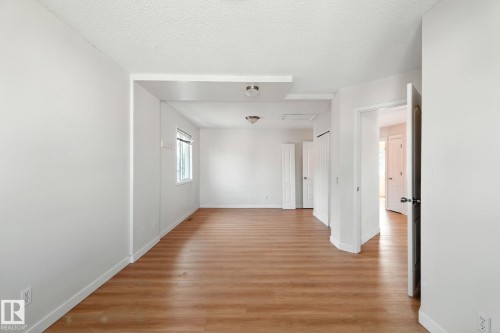 Empty room with light wood-style floors and a textured ceiling - 7836 7 Avenue, Edmonton, AB - Indoor Photo Showing Other Room