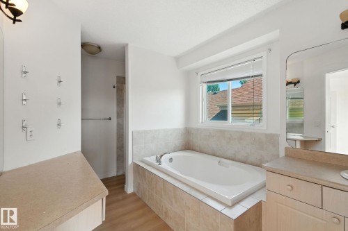 Bathroom with a garden tub, light wood-type flooring, and vanity - 7836 7 Avenue, Edmonton, AB - Indoor Photo Showing Bathroom