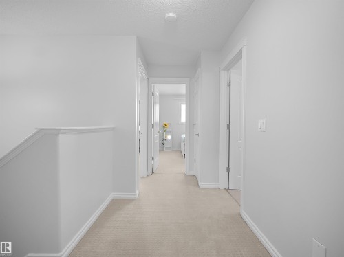 Corridor featuring light colored carpet, a textured ceiling, and an upstairs landing - 1716 64 Street, Edmonton, AB - Indoor Photo Showing Other Room