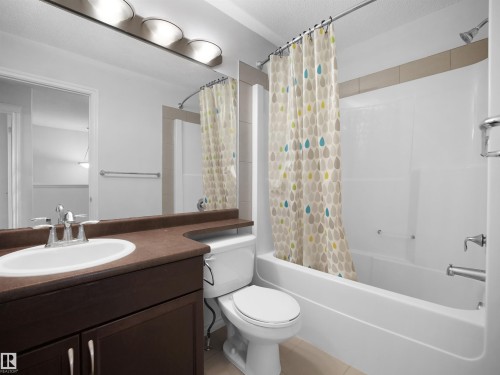 Bathroom with vanity, shower / bath combo with shower curtain, a textured ceiling, and light tile patterned flooring - 1716 64 Street, Edmonton, AB - Indoor Photo Showing Bathroom