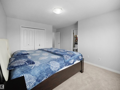 Bedroom featuring light carpet, a textured ceiling, a closet, and ensuite bathroom - 1716 64 Street, Edmonton, AB - Indoor Photo Showing Bedroom