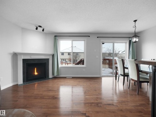 Living room featuring a fireplace, dark wood-style floors, a textured ceiling, and rail lighting - 1716 64 Street, Edmonton, AB - Indoor Photo Showing Living Room With Fireplace