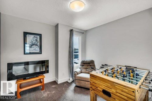 Rec room featuring dark carpet and a textured ceiling - 6485 King Wynd, Edmonton, AB - Indoor
