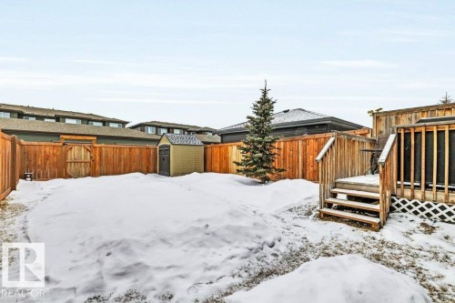 Yard layered in snow featuring a storage shed, a fenced backyard, and a wooden deck - 6485 King Wynd, Edmonton, AB - Outdoor