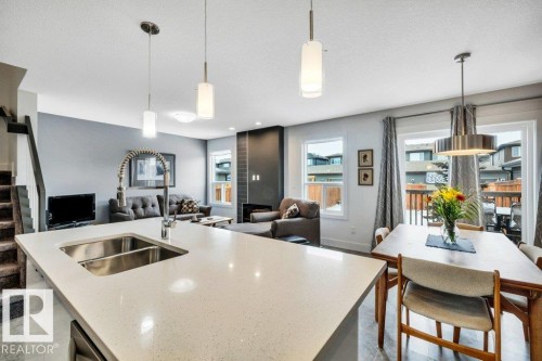 Kitchen with open floor plan, a kitchen island with sink, light stone countertops, and a textured ceiling - 6485 King Wynd, Edmonton, AB - Indoor