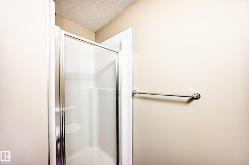 Full bathroom featuring a textured ceiling and a stall shower - 403 340 Windermere Road, Edmonton, AB - Indoor Photo Showing Bathroom
