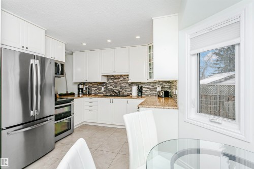 Kitchen with stainless steel appliances, light stone countertops, glass fronted cabinets, white cabinets, and recessed lighting - 18507 92 Avenue, Edmonton, AB - Indoor Photo Showing Kitchen With Stainless Steel Kitchen With Upgraded Kitchen