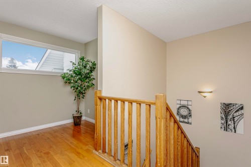 Hallway featuring light wood finished floors, an upstairs landing, and a textured ceiling - 18507 92 Avenue, Edmonton, AB - Indoor Photo Showing Other Room