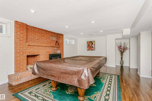 Playroom with a fireplace, billiards, dark wood finished floors, a textured ceiling, and recessed lighting - 18507 92 Avenue, Edmonton, AB - Indoor With Fireplace