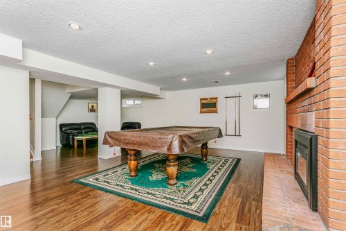 Recreation room featuring billiards table, a textured ceiling, wood finished floors, a fireplace, and recessed lighting - 18507 92 Avenue, Edmonton, AB - Indoor With Fireplace