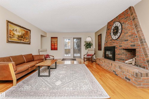 Living area featuring a brick fireplace, light wood finished floors, and a textured ceiling - 18507 92 Avenue, Edmonton, AB - Indoor Photo Showing Living Room With Fireplace