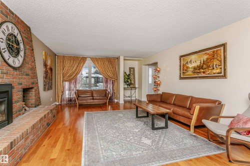 Living area with light wood-style flooring, a fireplace, and a textured ceiling - 18507 92 Avenue, Edmonton, AB - Indoor Photo Showing Living Room With Fireplace