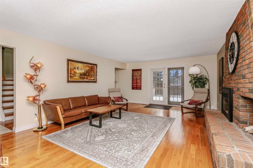 Living room with light wood-style flooring, a brick fireplace, and a textured ceiling - 18507 92 Avenue, Edmonton, AB - Indoor Photo Showing Living Room With Fireplace