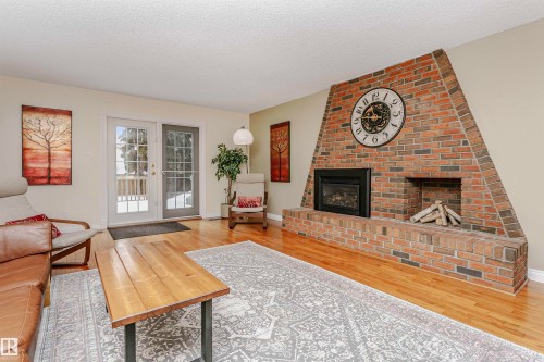 Living area with a brick fireplace, a textured ceiling, and light wood-style flooring - 18507 92 Avenue, Edmonton, AB - Indoor Photo Showing Living Room With Fireplace