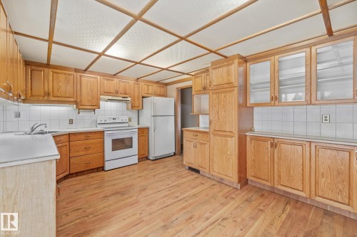 Kitchen with decorative backsplash, white appliances, and light countertops - 10971 157 Street, Edmonton, AB - Indoor Photo Showing Kitchen