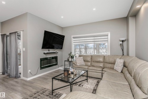 Living room with light wood-style floors, recessed lighting, and a glass covered fireplace - 7322 Chivers Crescent, Edmonton, AB - Indoor Photo Showing Living Room With Fireplace