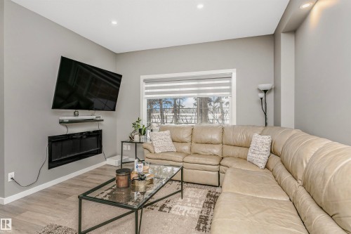 Living area featuring wood finished floors, a glass covered fireplace, and recessed lighting - 7322 Chivers Crescent, Edmonton, AB - Indoor Photo Showing Living Room With Fireplace