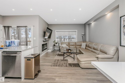 Living area with light wood finished floors, recessed lighting, and a glass covered fireplace - 7322 Chivers Crescent, Edmonton, AB - Indoor Photo Showing Living Room