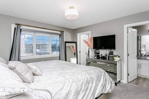 Bedroom featuring light colored carpet, a textured ceiling, and ensuite bath - 7322 Chivers Crescent, Edmonton, AB - Indoor Photo Showing Bedroom