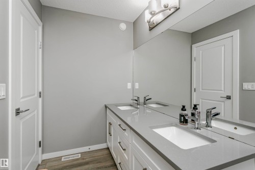 Bathroom with double vanity, wood finished floors, and a textured ceiling - 7322 Chivers Crescent, Edmonton, AB - Indoor