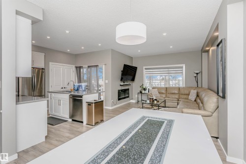 Living room with a glass covered fireplace, light wood-style floors, recessed lighting, and a textured ceiling - 7322 Chivers Crescent, Edmonton, AB - Indoor