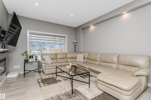 Living area featuring light wood-style floors, a glass covered fireplace, and recessed lighting - 7322 Chivers Crescent, Edmonton, AB - Indoor Photo Showing Living Room With Fireplace