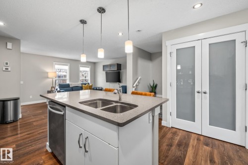 Kitchen with white cabinetry, dark wood-style flooring, dark stone counters, pendant lighting, and open floor plan - 1315 Chappelle Boulevard, Edmonton, AB - Indoor Photo Showing Kitchen With Double Sink