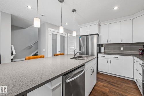 Kitchen with stainless steel appliances, white cabinetry, pendant lighting, and a textured ceiling - 1315 Chappelle Boulevard, Edmonton, AB - Indoor Photo Showing Kitchen With Double Sink With Upgraded Kitchen