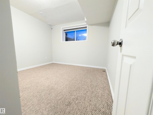 Carpeted spare room featuring a textured ceiling and baseboards - 3307 24 Avenue, Edmonton, AB - Indoor Photo Showing Other Room