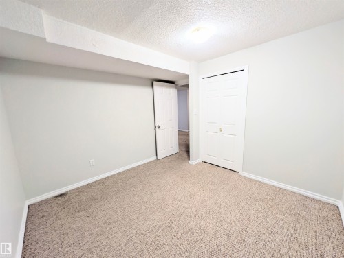 Unfurnished bedroom with a textured ceiling, carpet flooring, and a closet - 3307 24 Avenue, Edmonton, AB - Indoor Photo Showing Other Room