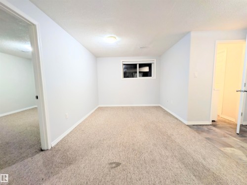 Spare room featuring a textured ceiling and light colored carpet - 3307 24 Avenue, Edmonton, AB - Indoor Photo Showing Other Room