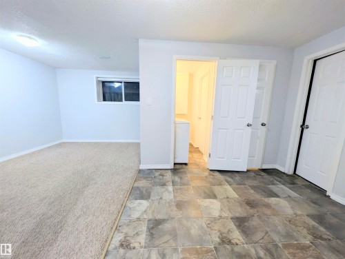 Unfurnished bedroom with stone finish floors, a textured ceiling, a closet, washer / dryer, and carpet flooring - 3307 24 Avenue, Edmonton, AB - Indoor Photo Showing Other Room