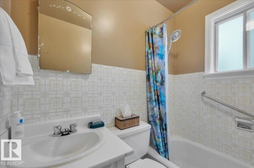 Full bathroom featuring tile walls, shower / bath combo, and wainscoting - 7934 81 Avenue Nw, Edmonton, AB - Indoor Photo Showing Bathroom