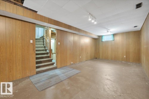 Below grade area with track lighting and wood walls - 7934 81 Avenue Nw, Edmonton, AB - Indoor Photo Showing Basement