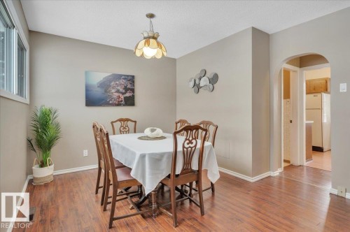 Dining room featuring arched walkways, wood finished floors, and a textured ceiling - 7934 81 Avenue Nw, Edmonton, AB - Indoor Photo Showing Dining Room