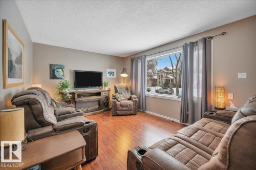 Living area featuring wood-type flooring and a textured ceiling - 7934 81 Avenue Nw, Edmonton, AB - Indoor Photo Showing Living Room