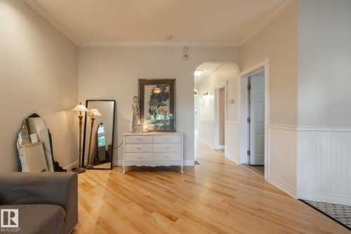 Bedroom with arched walkways, light wood-type flooring, ornamental molding, and wainscoting - 11415 85 Street, Edmonton, AB - Indoor Photo Showing Other Room