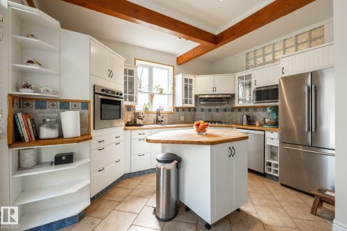 Kitchen with white cabinetry, open shelves, stainless steel appliances, decorative backsplash, and beam ceiling - 11415 85 Street, Edmonton, AB - Indoor Photo Showing Kitchen With Upgraded Kitchen