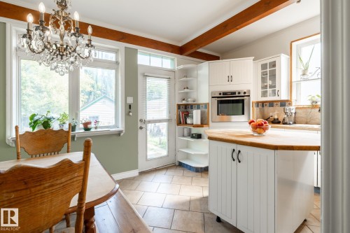 Kitchen featuring white cabinets, stainless steel oven, backsplash, open shelves, and ornamental molding - 11415 85 Street, Edmonton, AB - Indoor