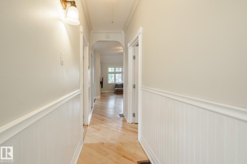 Hall featuring wainscoting, arched walkways, light wood-type flooring, and crown molding - 11415 85 Street, Edmonton, AB - Indoor Photo Showing Other Room