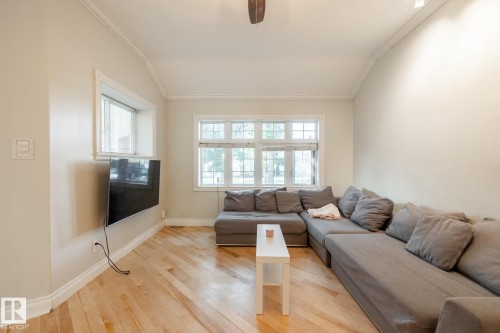 Living room featuring light wood finished floors, healthy amount of natural light, crown molding, and a ceiling fan - 11415 85 Street, Edmonton, AB - Indoor Photo Showing Living Room