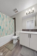 Bathroom featuring vanity, a textured ceiling, shower / bath combo with shower curtain, and wood finished floors - 