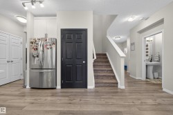 Kitchen featuring stainless steel fridge with ice dispenser, a textured ceiling, and light wood finished floors - 