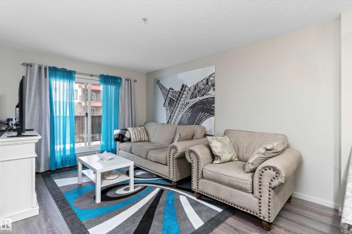 Living area featuring dark wood-type flooring and a textured ceiling - 231 344 Windermere Road, Edmonton, AB - Indoor Photo Showing Living Room