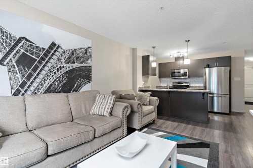 Living room with dark wood-style floors and a textured ceiling - 231 344 Windermere Road, Edmonton, AB - Indoor