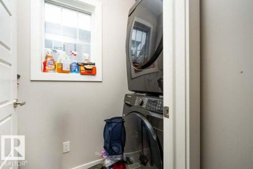Laundry area with stacked washer / dryer and baseboards - 96 1530 Tamarack Boulevard, Edmonton, AB - Indoor Photo Showing Laundry Room