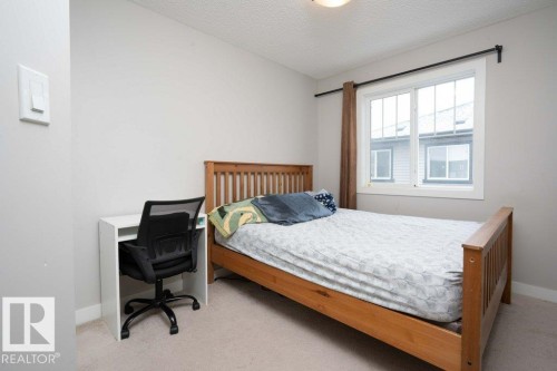 Bedroom with light colored carpet, a textured ceiling, and an office area - 96 1530 Tamarack Boulevard, Edmonton, AB - Indoor Photo Showing Bedroom