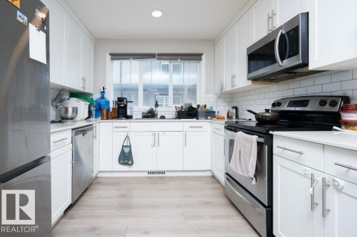 Kitchen with stainless steel appliances, white cabinetry, backsplash, light wood-style flooring, and recessed lighting - 96 1530 Tamarack Boulevard, Edmonton, AB - Indoor Photo Showing Kitchen With Upgraded Kitchen