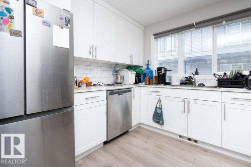 Kitchen with stainless steel appliances, light wood-style floors, white cabinets, and backsplash - 96 1530 Tamarack Boulevard, Edmonton, AB - Indoor Photo Showing Kitchen
